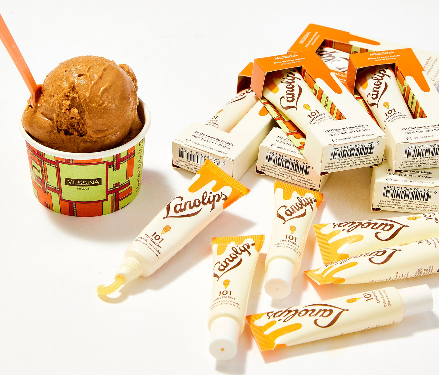 A collection of Lanolips 101 Ointment tubes and packaging in the limited-edition Dulce de Leche Gelato design, created in collaboration with Messina. To the left, a cup of Messina’s Dulce de Leche Gelato, sits with a caramel-coloured scoop and an orange spoon. Made with ultra-pure lanolin, vitamin e and all natural caramel flavour, this multipurpose balm deeply hydrates while embracing a sweet, dessert-inspired theme.