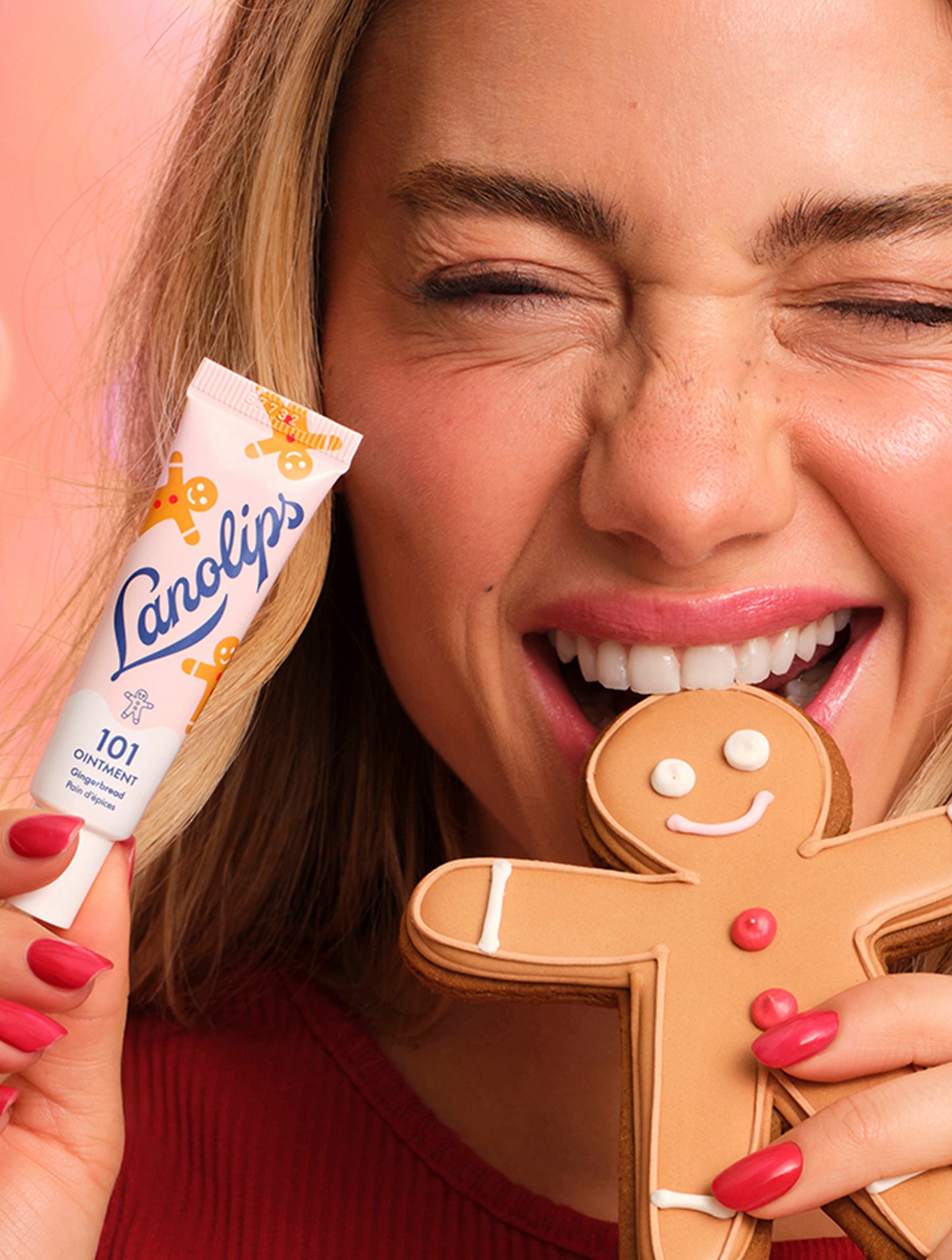 Model eating a gingerbread man cookie and a tube of Lanolips 101 Ointment Multi-Balm Gingerbread with a smiley face. Infused with a ginger blissed twist, combining hydrating lanolin and vitamin-e for the sweetest swipe ever.