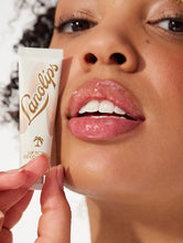 Load image into Gallery viewer, Model holding Lanolips Lip Scrub Coconutter and with the mixture of ultra-pure grade lanolin, finely grated coconut shell pieces and sugar, it leaves your lips deeply hydrated.
