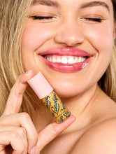 Load image into Gallery viewer, Model smiling while holding Lanolips Hyaluronic Lip Oil Honey, showing glossy, hydrated lips with a radiant finish
