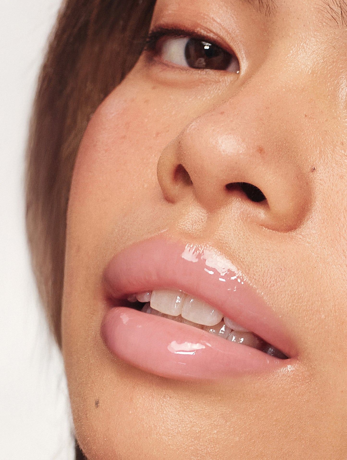 Close-up of a model’s lips wearing Lanolips Milkshake Ceramide Balm in Strawberry Bubble, showing a glossy pink finish and hydrated, smooth texture.