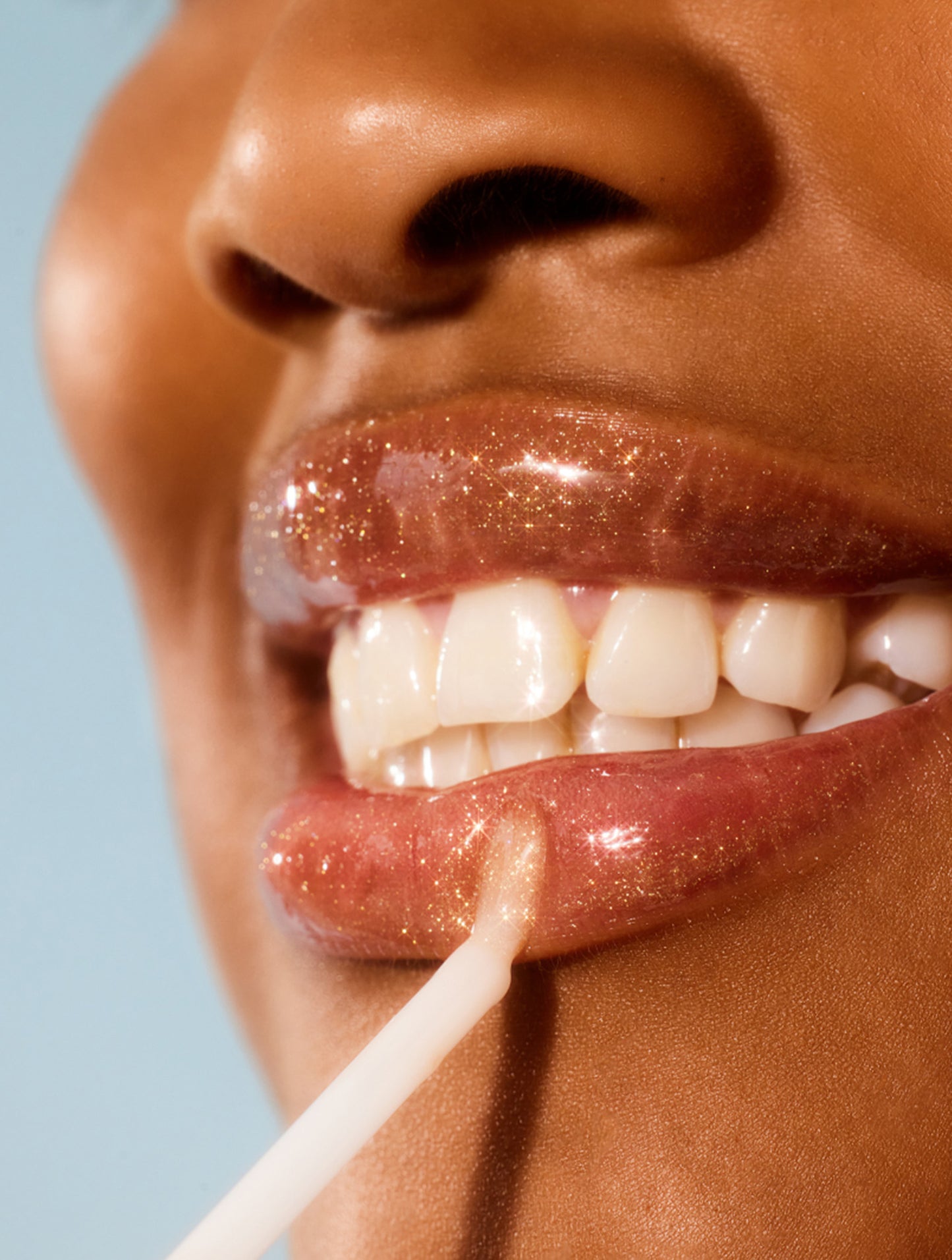 Model applying lanolips liquid lanolin lip water liquid gold to her lips.