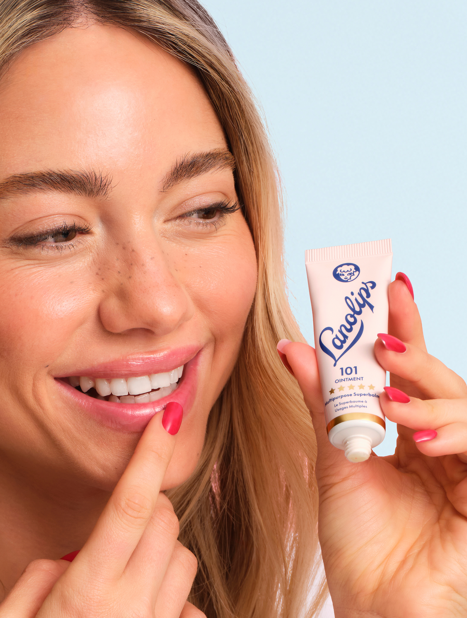 Model holding a lanolips 101 ointment multipurpose superbalm tube in her hand.
